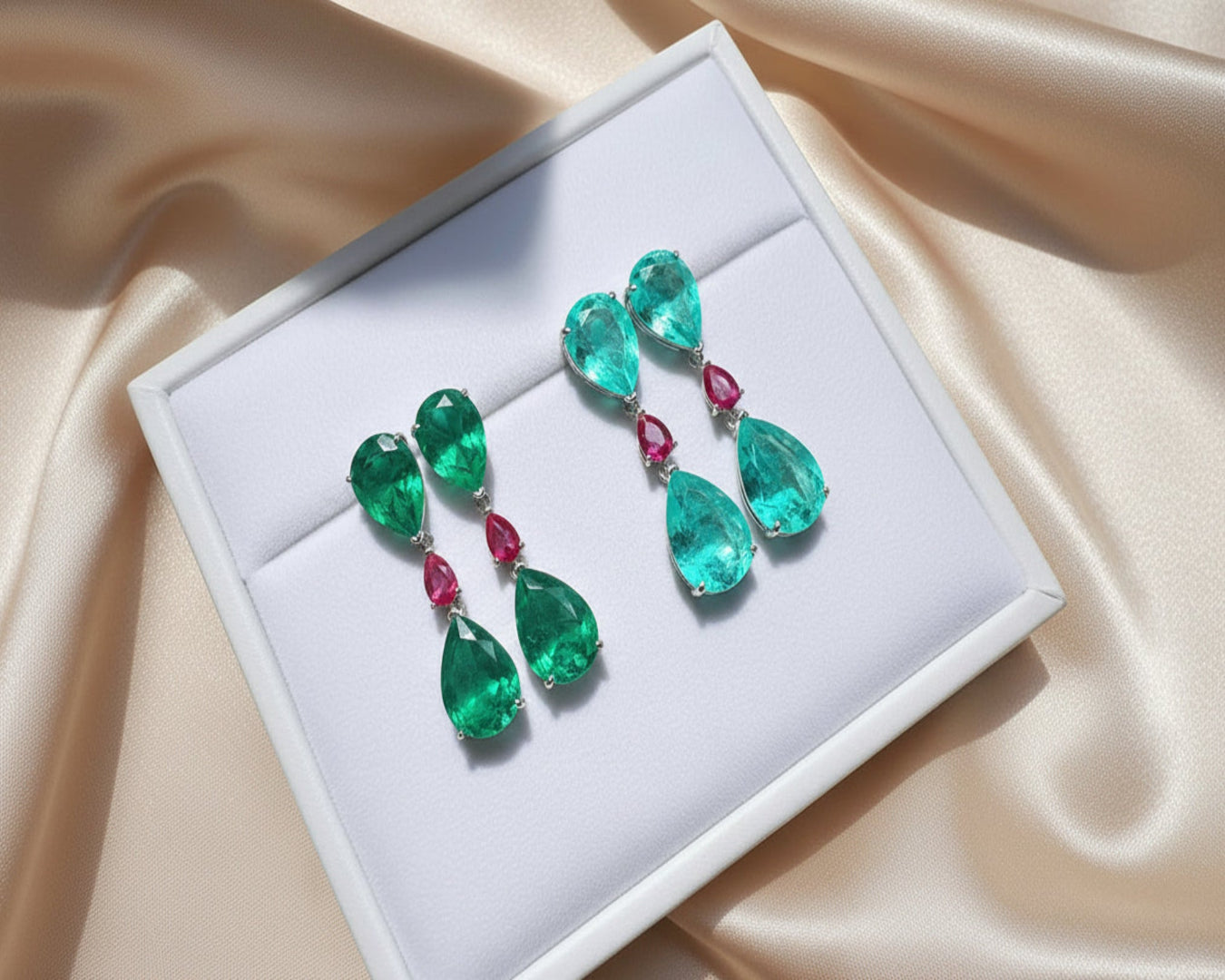 Pair of emerald and ruby earrings on a white display box