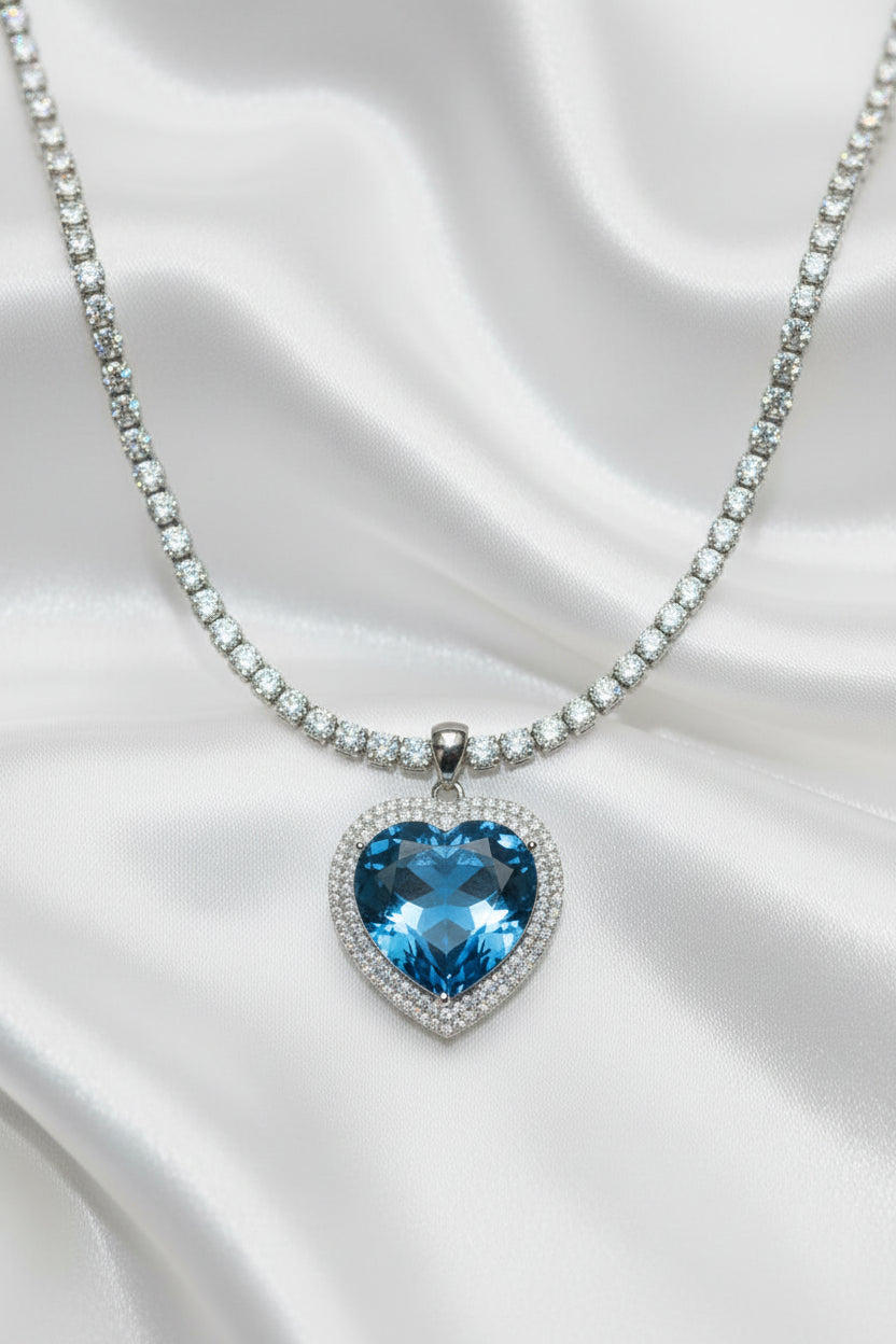 Necklace with a blue heart-shaped gemstone pendant on a white satin background