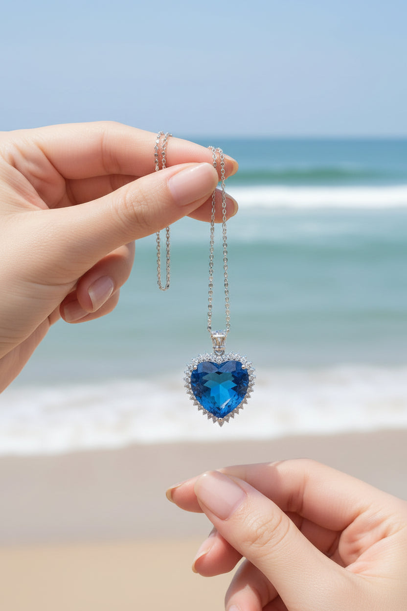 Blue heart-shaped gemstone pendant on a chain against a dark background