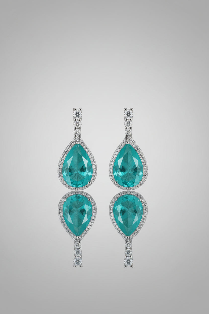 Turquoise teardrop earrings with silver accents on a white and gray braided background