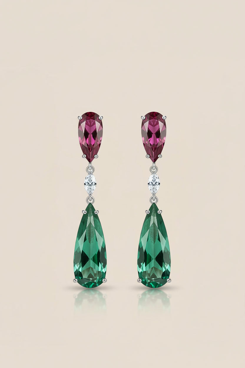 Pair of teardrop-shaped gemstone earrings with pink and green stones on a beige background