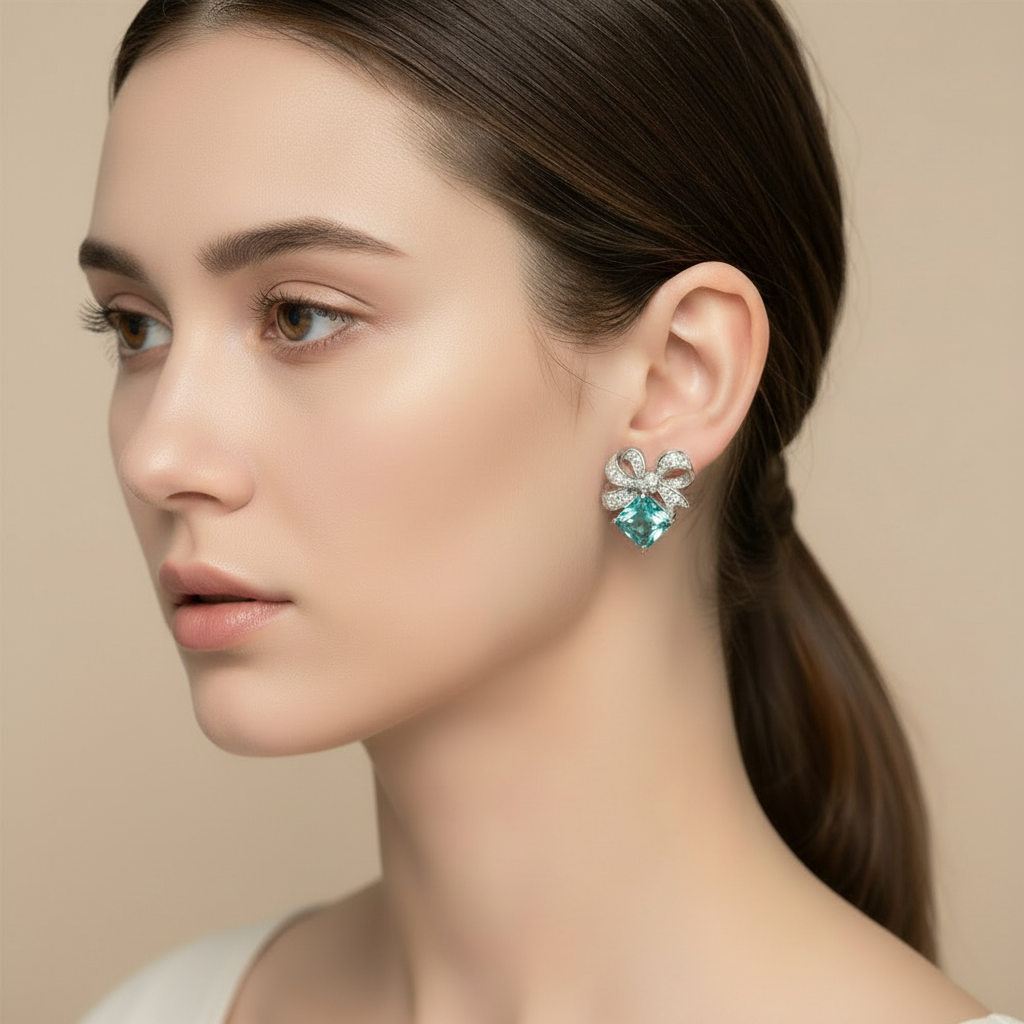 Close-up of a woman wearing a pair of earrings with a green gemstone against a beige background