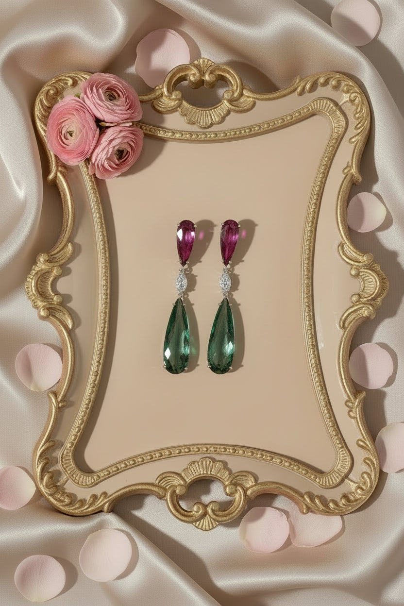 Pair of earrings with pink and green gemstones on a white background