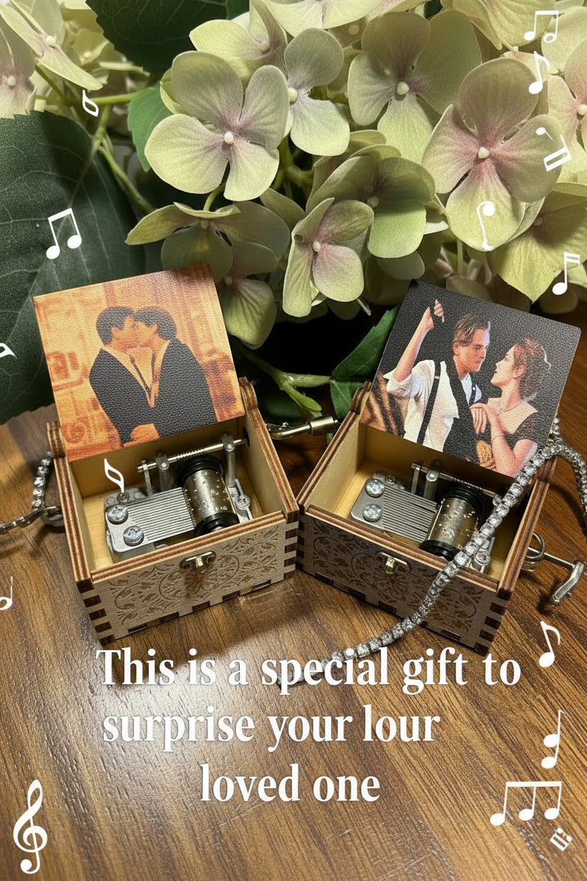 Two vintage-style music boxes with romantic scenes on top, surrounded by green leaves.