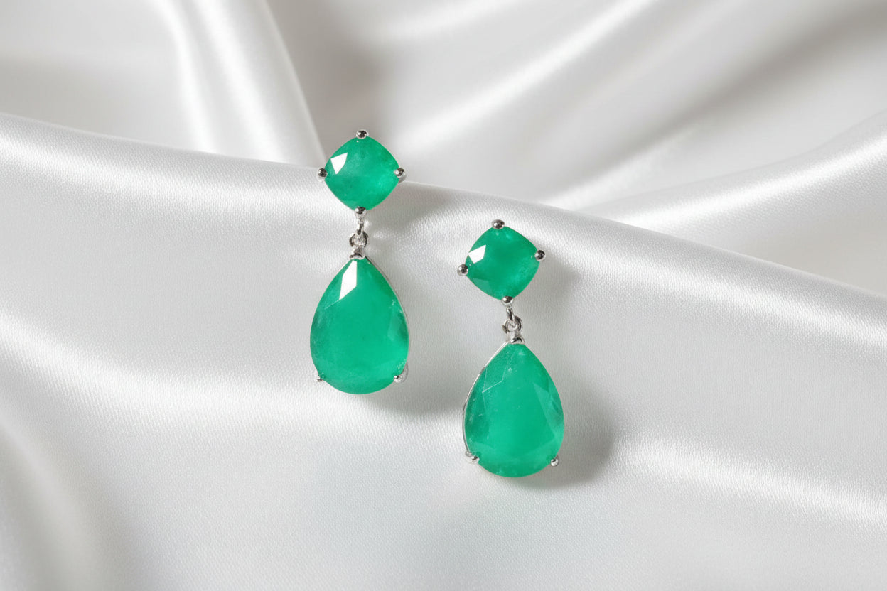 Green gemstone earrings on a green stem with a green background
