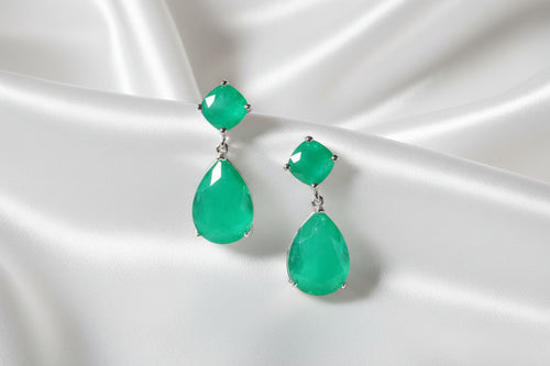 Green gemstone earrings on a green stem with a green background