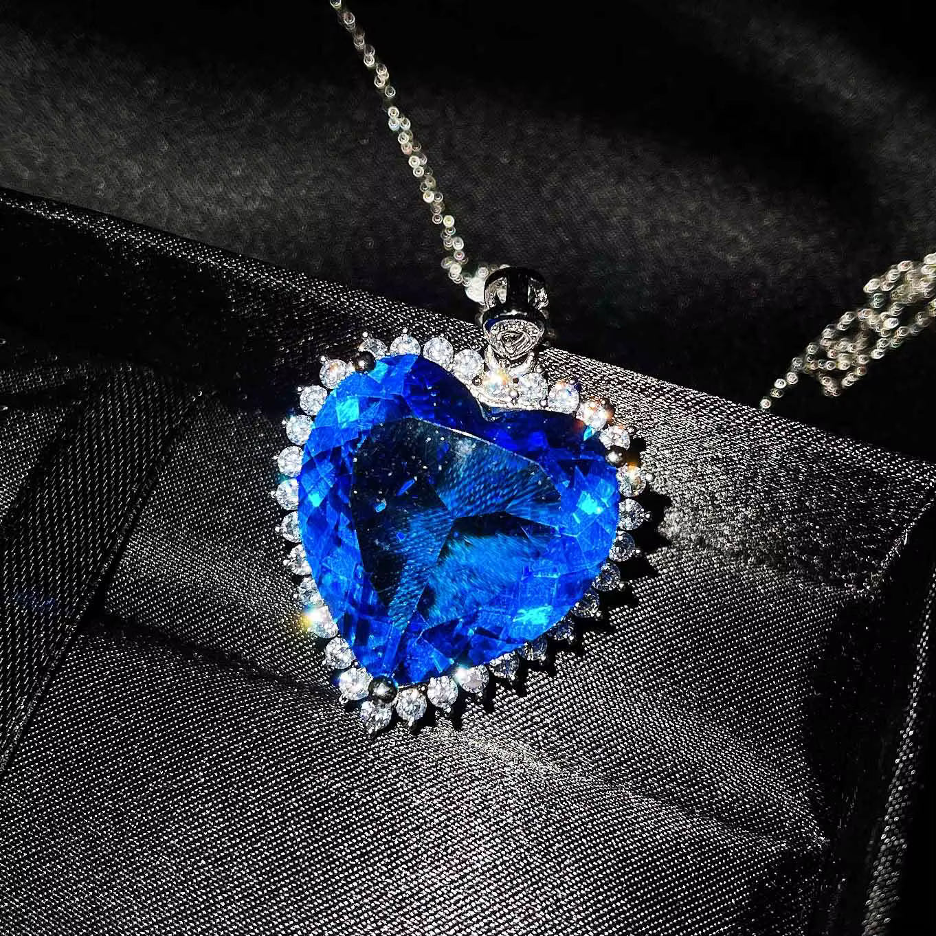 Blue heart-shaped gemstone necklace on a textured black surface